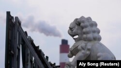 资料照 - 透过一座威严 的石狮雕像，可以看到上海附近的一座火力发电厂冒出的滚滚浓烟。照片来自路透社，拍摄时间是2021年10月21日。