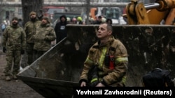 (FILE) An emergency worker rests near an apartment block was damaged by a Russian missile strike in Ukraine.