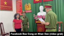 Nhà báo Hàn Ni (áo đỏ) nghe một viên chức công an đọc quyết định bắt tạm giam, khởi tố bà về cáo buộc lợi dụng các quyền tự do dân chủ, tại Thành phố Hồ Chí Minh, ngày 24 tháng 2, 2023.