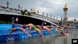 Sejumlah atlet melompat ke dalam sungai Seine saat kompetisi triathlon novor individu putri dimulai di Olimpiade Paris, pada 31 Juli 2024. (Foto: AP/Vadim Ghirda)