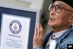 Seiichi Sano, an 89-year-old Japanese man who has been recognized by Guinness World Records as the oldest male to surf, shows his Guinness certificate at Katase Beach, Thursday, March 30, 2023, in Fujisawa, south of Tokyo. (AP Photo/Eugene Hoshiko)