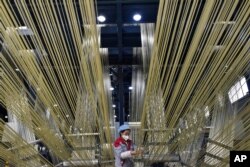 Seorang pekerja mengatur filamen mentah di basis produksi Zhongfu Shenying Carbon Fiber Co., Ltd. di Xining, Provinsi Qinghai, China barat laut pada 22 Februari 2023. (Wu Gang/Xinhua via AP)