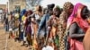 FILE - Women who fled the war-torn Sudan line up to receive food rations at the United Nations High Commissioner for Refugees transit center near the border crossing point in Renk County of Upper Nile State, South Sudan May 1, 2023. 