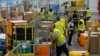 Empleados de Amazon cargan paquetes antes de colocarlos en camiones para los clientes de distribución para el evento anual Prime Day de Amazon en una estación de entrega DAX7 de Amazon el martes 16 de julio de 2024, en South Gate, California (Foto AP/Richard Vogel)