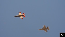 An AI-enabled Air Force F-16 fighter jet, left, flies next to a mock adversary F-16, trying to force its opponent into vulnerable positions, above Edwards Air Force Base, California, May 2, 2024.