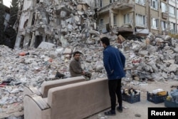 Survivors salvage belongings from their apartment building destroyed in a devastating earthquake, in Antakya, southeastern Turkey, Feb. 20, 2023.
