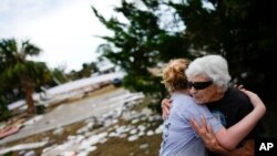 Tina Brotherton, 88, gets a hug from 9-year-old neighbor Lainey Hamelink, as she returns to site of her business, Tina's Dockside Inn, which was destroyed in Hurricane Idalia, as was Brotherton's nearby home, in Horseshoe Beach, Fla., Sept. 1, 2023.