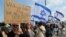 Israeli protesters lift national flags and placards as they rally in Tel Aviv on Feb. 13, 2023, against controversial legal reforms being touted by the country's hard-right government.