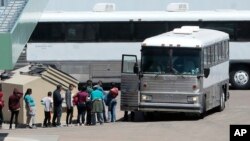 FILE - In this April 20, 2019, photo, migrants are loaded onto a bus at the Border Patrol headquarters on Hondo Pass, in El Paso, Texas. 