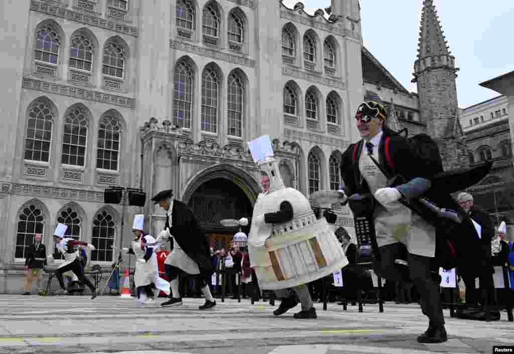 Workers from different City Company professions take part in the Shrove Tuesday Inter-Livery Pancake Race at the Guildhall in the City of London.