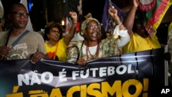 People hold a banner with a message that reads in Portuguese: "It isn't football, it is racism" during a protest against racism suffered by Brazilian soccer star Vinicius Junior who plays for Spain's Real Madrid, in Rio de Janeiro, Brazil, May 25, 2023.