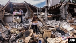 Mustafa Ozdimir helps his family as they collect goods from their collapsed shop in the city of Antakya on Feb. 19, 2023. 