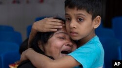Rakibul, 6, comforts his mother Rehana mourning the death of her husband, Mohammad Zillur, at a hospital in Munshiganj, outside Dhaka. Zillur, a supporter of a candidate from the ruling Awami League, was stabbed to death as Bangladesh voted in a parliamentary election boycotted by the main opposition party.