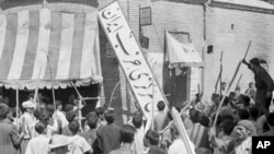 FILE - A crowd of demonstrators tears down the Iran Party's sign from the front of the headquarters in Tehran on Aug. 19, 1953, during the CIA-backed coup that ousted Prime Minister Mohammad Mossadegh and his government. 