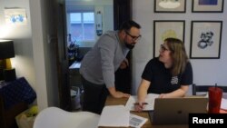 Ghenya Grondin consults with her husband Jonathan while meeting virtually with a physical therapist to address her post-exertional malaise (PEM) symptoms, at their home in Waltham, Massachusetts, Dec. 16, 2022.