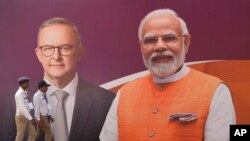 Policemen walk past a sign featuring Australian Prime Minister Anthony Albanese and Indian Prime Minister Narendra Modi in Ahmedabad, India, March 8, 2023.