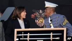 El cadete Melic Belong entrega a la vicepresidenta Kamala Harris un recuerdo durante la ceremonia de graduación de los cadetes de la academia militar de Estados Unidos en West Point, Nueva York, sábado 27 de mayo de 2023. (AP Foto/Bryan Woolston)