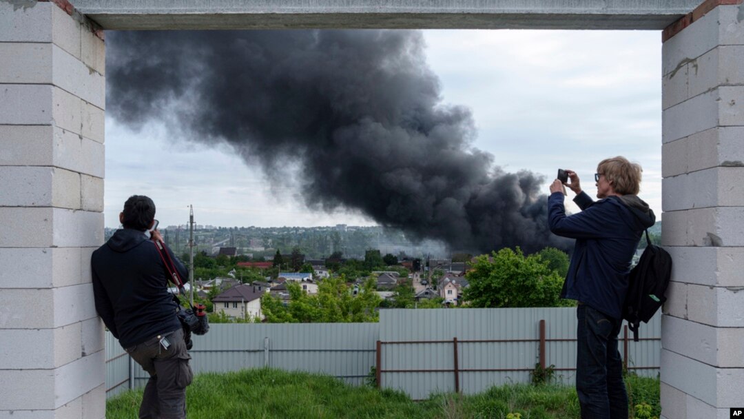 Foreign journalists report from an observation point while smoke rises after a Russian attack in Kharkiv, Ukraine, May 17, 2024.