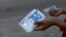 FILE — A person holds a 1000 Naira note as the Central Bank of Nigeria releases the notes to the public through the banks in Abuja, Nigeria, on December 15, 2022. 