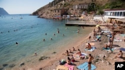 FILE - People gather at the beach area of the Black Sea, in Balaklava's bay, a part of Sevastopol on the Crimean Peninsula, Aug. 9, 2015. The peninsula's beaches have been vacation spots for Russian czars and has hosted key meetings of world leaders.