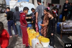Palestinians line up to fill containers with water in Rafah on the southern Gaza Strip on March 17, 2024.