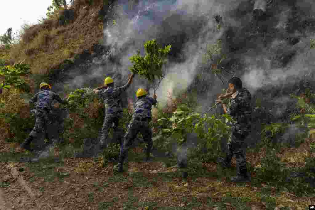 Police officers douse a forest fire in Shivapuri National Park on the outskirts of of in Lalitpur, Nepal.