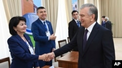 In this handout photo released by Uzbekistan's Presidential Press Office, Uzbekistan's President Shavkat Mirziyoyev greets members of an election commicion at a polling station during a referendum in Tashkent, Uzbekistan, April 30, 2023. 