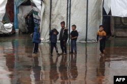 Anak-anak Palestina bermain di tengah hujan di kamp pengungsi di Rafah. (Foto: AFP)