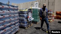 A man walks next to humanitarian aid destined for the Gaza Strip, amid the ongoing conflict in Gaza between Israel and Hamas, at the Kerem Shalom crossing in southern Israel, July 10, 2024.