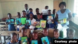 Dekezi Primary School head and some pupils display books received from the Zimbabwe Rural Schools Library Trust