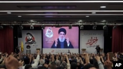 FILE - Supporters of the Iranian-backed Hezbollah group listen to a speech by Hezbollah leader Sayyed Hassan Nasrallah speaking via a video link, in the southern suburbs of Beirut, May 14, 2024.