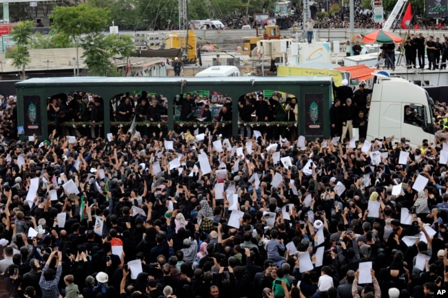 Mourners surround a truck carrying the flag-draped coffins of the President Ebrahim Raisi, and his companions who were killed in a helicopter crash on Sunday, during their funeral ceremony in the city of Mashhad, Iran, May 23, 2024.