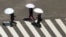 People holding parasols cross a street in scorching heat at Ginza district in Tokyo, Japan, Aug. 4, 2023.