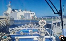 Sebuah kapal Penjaga Pantai China, di depan, diduga memblokir jalur kapal Penjaga Pantai Filipina di dekat Second Thomas Shoal yang diduduki Filipina, Laut China Selatan, 5 Agustus 2023. (Foto: via AP)