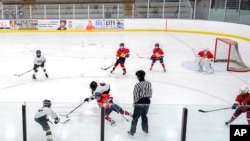 FILE - Players on the Minneapolis, wearing white and black uniforms, and Orono, wearing red uniforms, teams compete in a 10-and-under youth hockey game in Minneapolis, Feb. 4, 2024.