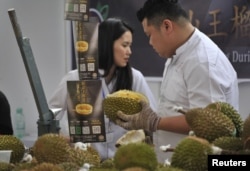FILE - Promoters offer durians at a booth in Nanning, Guangxi Zhuang Autonomous Region, China, Nov. 4, 2017.