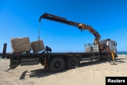 Pekerja Palestina menyiapkan balok beton yang akan digunakan untuk membangun dermaga sementara, di tengah konflik yang sedang berlangsung antara Israel dan Hamas, di Khan Younis di selatan Jalur Gaza, 12 Maret 2024. (Foto: Reuters)