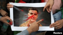 FILE - Afghan nationals paint over a picture of Pakistan's former spy chief, Faiz Hameed, as they hold a protest near a police station in New Delhi, Sept. 10, 2021. Pakistan announced on Aug. 12, 2024, the arrest of the retired general. 