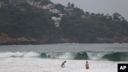 Wisatawan berenang di Acapulco, Meksiko, Selasa, 24 Oktober 2023. Badai Otis semakin kuat dari badai tropis menjadi badai besar dalam hitungan jam saat mendekati pantai Pasifik selatan Meksiko yang diperkirakan akan mendarat di kawasan ini Rabu dini hari.(AP/Bernardino Hernandez)