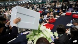 National Election Commission officials empty a box containing ballots for parliamentary election as they prepare the counting process in Seoul, South Korea, April 10, 2024.