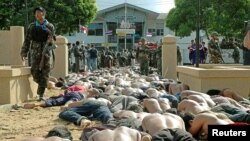 FILE - A Thai soldier walks by hundreds of men arrested after they clashed with police outside the Tak Bai police station in Thailand's Narathiwat province, some 1,150 km south of Bangkok, Oct. 25, 2004.