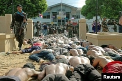 FILE - A Thai soldier walks by hundreds of men arrested after they clashed with police outside the Tak Bai police station in Thailand's Narathiwat province, some 1,150 km south of Bangkok, Oct. 25, 2004.