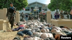 FILE - A Thai soldier walks by hundreds of men arrested after they clashed with police outside the Tak Bai police station in Thailand's Narathiwat province, some 1,150 km south of Bangkok, Oct. 25, 2004.