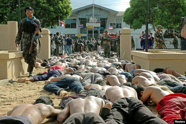 FILE - A Thai soldier walks by hundreds of men arrested after they clashed with police outside the Tak Bai police station in Thailand's Narathiwat province, some 1,150 km south of Bangkok, Oct. 25, 2004.