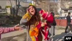 This image grab from a UGC video posted outside Iran on March 15, 2023, shows Iranian activist and journalist Sepideh Gholian walking with a bouquet of flowers outside the walls of Evin prison in Tehran, following her release. She was later rearrested.