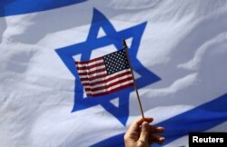 Bendera AS dan bendera Israel dikibarkan oleh demonstran untuk menunjukkan dukungan kepada Presiden AS Joe Biden, karena tidak mengundang Perdana Menteri Israel Benjamin Netanyahu ke Gedung Putih, di depan Konsulat AS di Tel Aviv, Israel, 30 Maret 2023. (Foto: REUTERS/Ronen Zvulun)