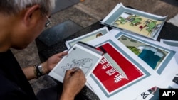 FILE - This picture taken on June 20, 2020 shows political cartoonist Wong Kei-kwan using an electronic pad to draw an illustration in Hong Kong.