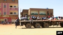 People fleeing street battles between the forces of two rival Sudanese generals are transported on the back of a truck in the southern part of Khartoum.