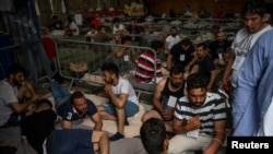 Migrants who were rescued at open sea off the coast of Greece after their boat capsized are seen inside a warehouse, used as a shelter, at the port of Kalamata, Greece, June 15, 2023.