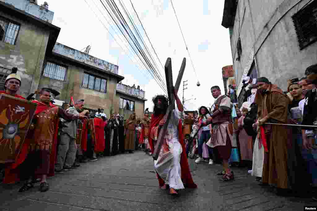 La gente presencia la recreación de la crucifixión de Jesucristo durante la procesión del Viernes Santo en el barrio de Petare, en Caracas, Venezuela.